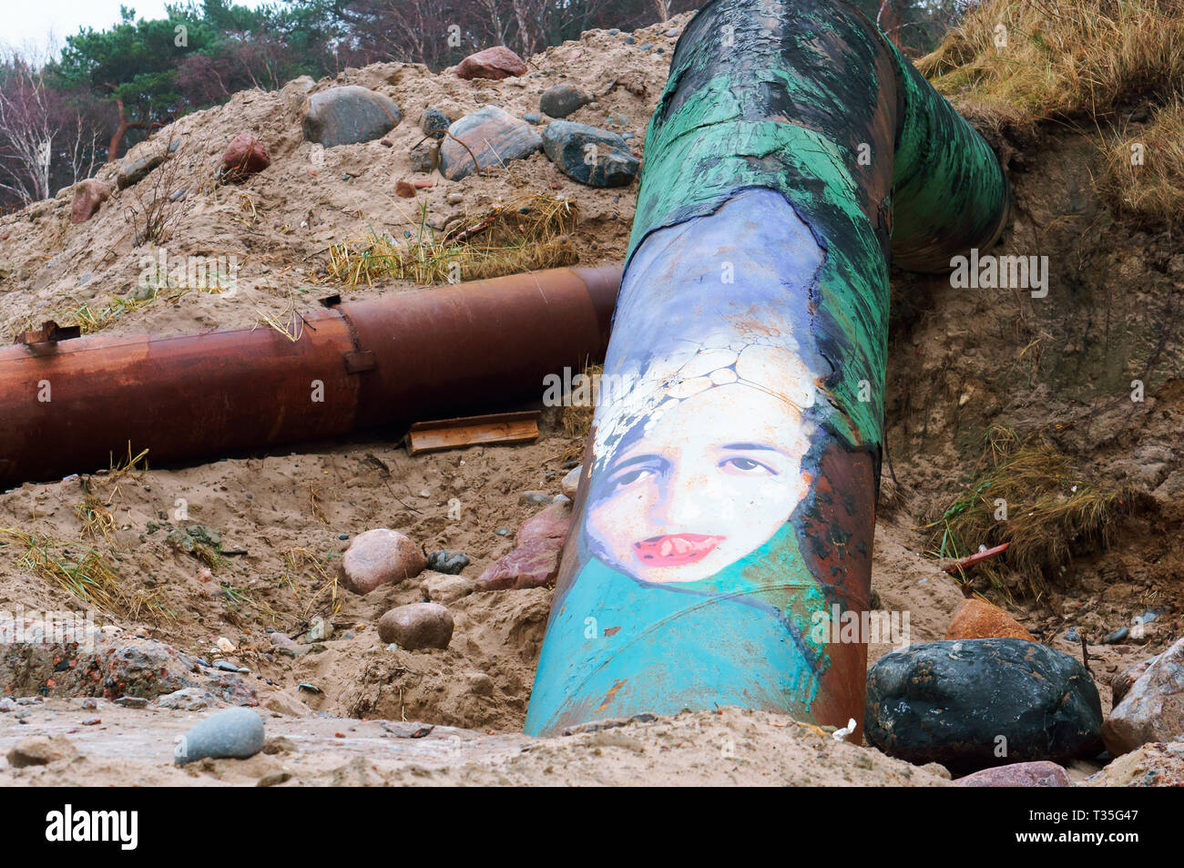 Graffiti sur un tuyau rouillé, visage de la fille peinte sur le tuyau, côte de la mer Baltique, région de Kaliningrad, Russie, le 25 novembre, 2018 Banque D'Images