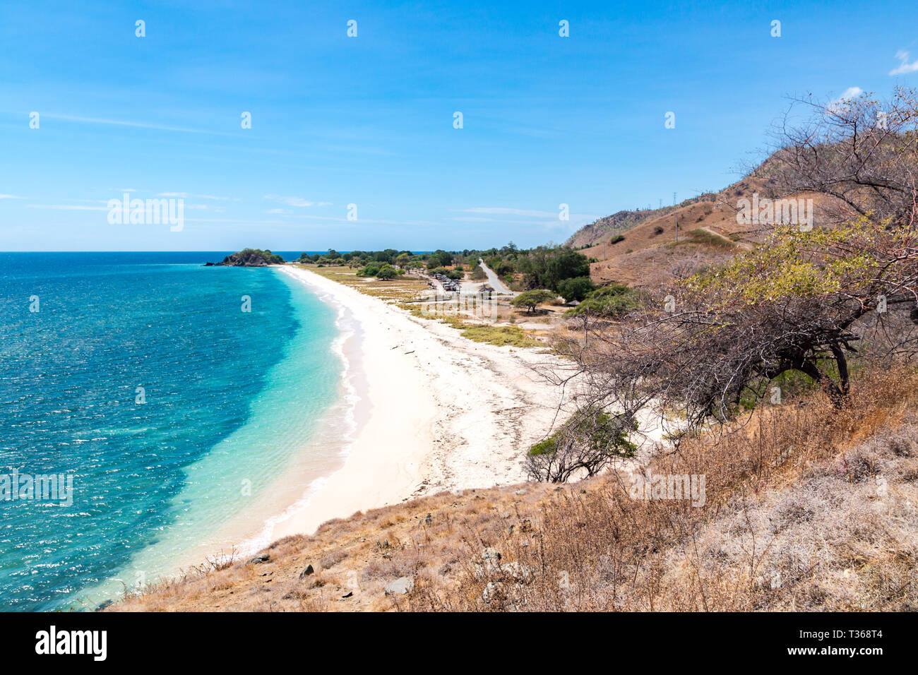L'un dollar beach. Plage de sable jaune Idillic du Timor oriental, au Timor-Leste. Littoral avec des collines, des montagnes et la savane sèche. Paysage rural et la nature b Banque D'Images