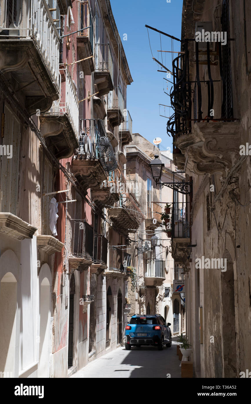 Scène de rue ville petite voiture roulant le long de la coursive ouvragée par Dione dans Ortigia, Syracuse, Sicile Banque D'Images