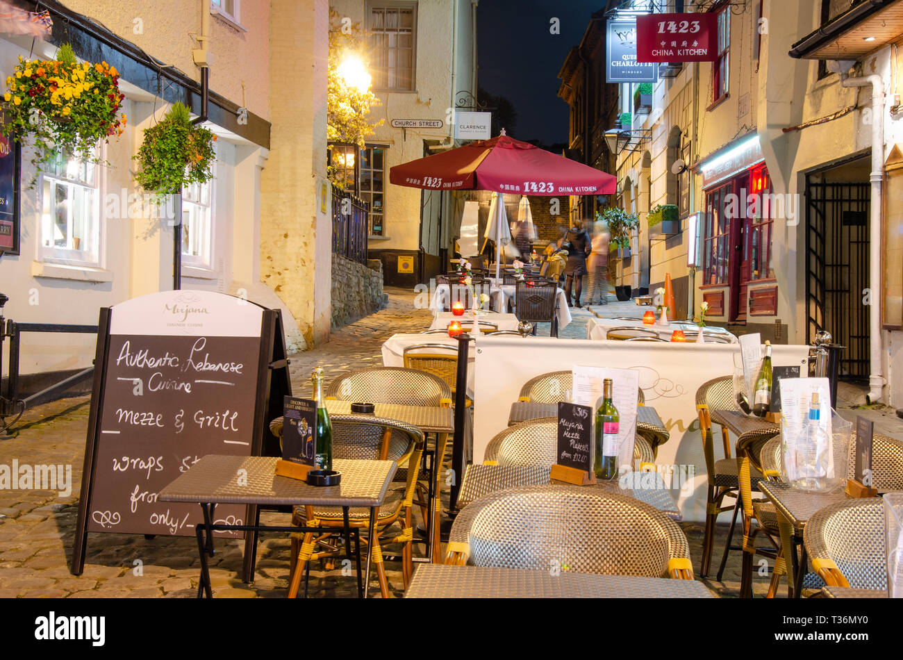 Configuration de table et chaises pour manger dehors en face de restaurants dans Church Lane, Windsor, Royaume-Uni la nuit. Banque D'Images