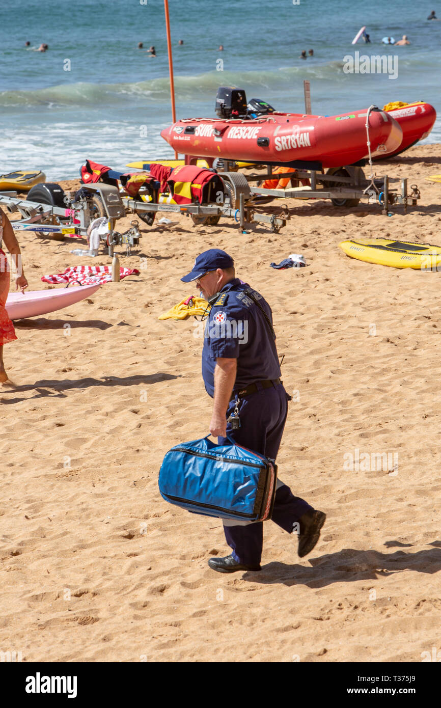 Paramédic masculins sur Palm beach vers une quasi-noyade victime qui a été sauvé par les bénévoles de surf,Palm Beach, Sydney, Australie Banque D'Images