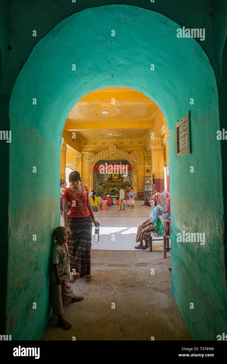 Femme birmane marche à travers un passage dans l'enceinte de la pagode Shwe Maw Yin près de Thazi, Myanmar (Birmanie). Banque D'Images
