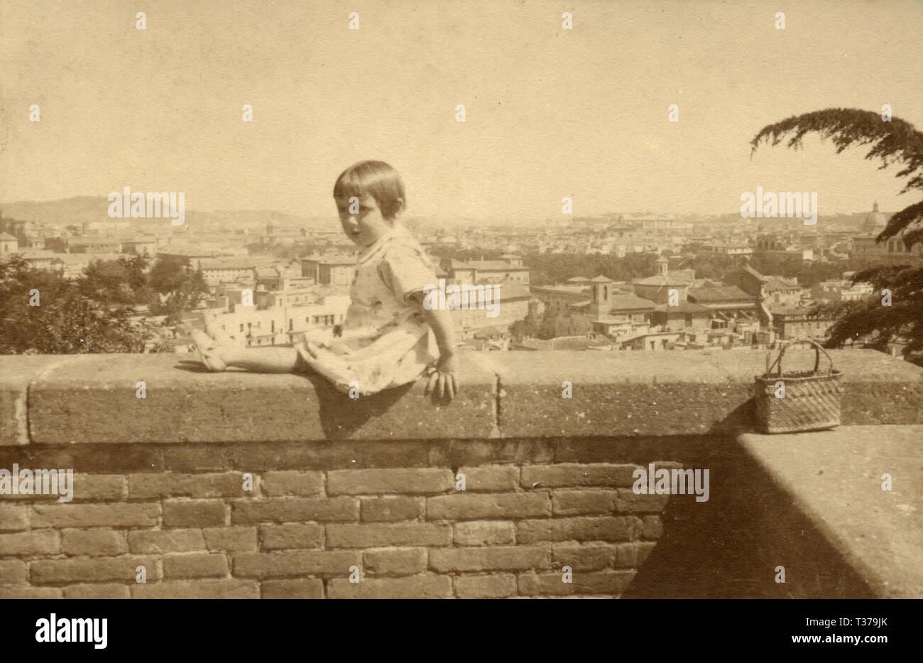 Petite fille assise sur un mur à Gianicolo, Rome, Italie 1920 Banque D'Images