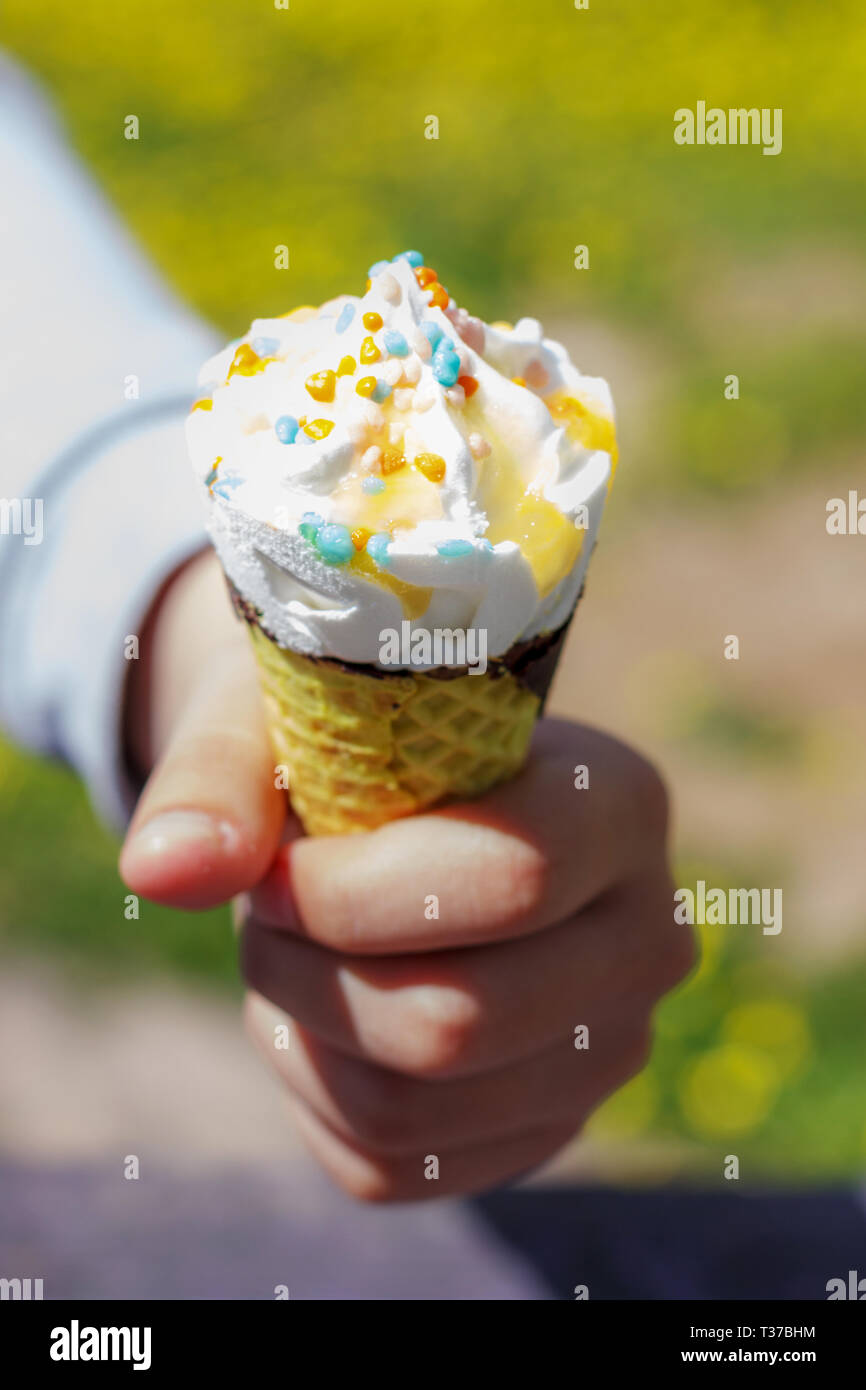 Main courante de la crème glacée en cornet gaufré en été sous le soleil. Banque D'Images