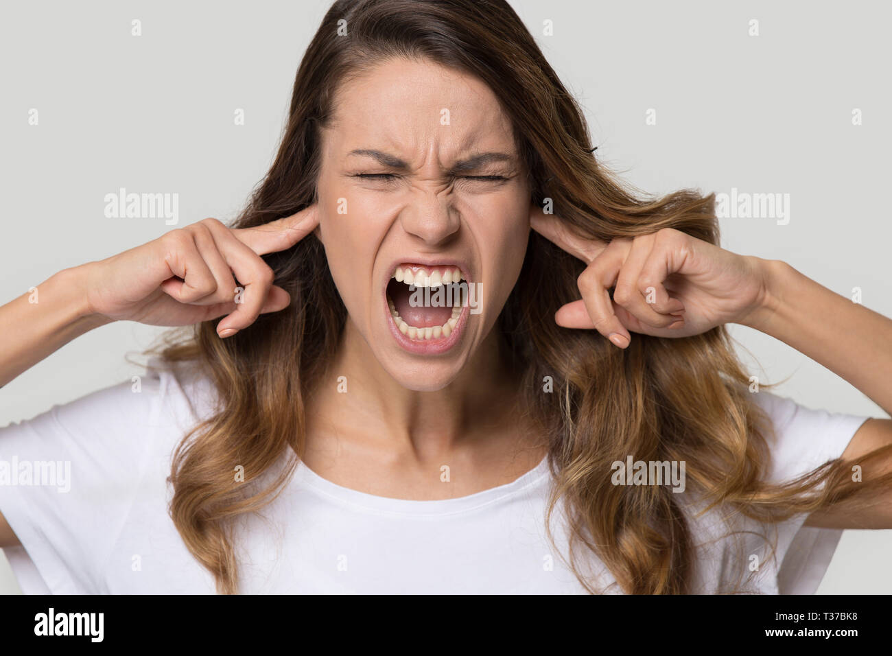 Portrait de femme hurlant fermer les oreilles avec les doigts Banque D'Images