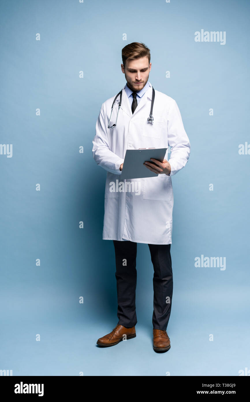 Médecin Homme debout avec dossier, Doc est le port de l'uniforme blanc et une cravate, se dresse sur un fond bleu clair. Banque D'Images
