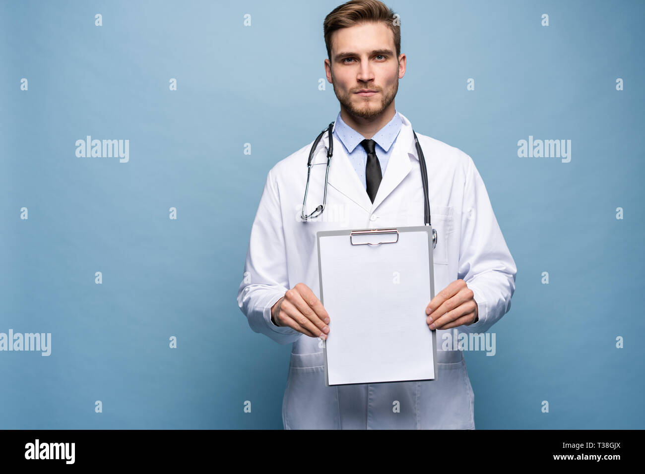 Médecin Homme debout avec dossier, Doc est le port de l'uniforme blanc et une cravate, se dresse sur un fond bleu clair. Banque D'Images