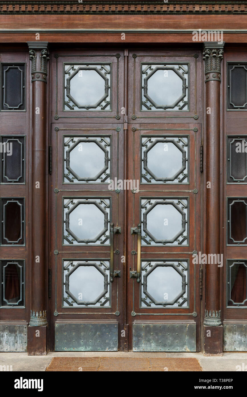 Ancien en bois massif portes battantes vitrées avec des ornements métalliques dans le bâtiment historique Banque D'Images