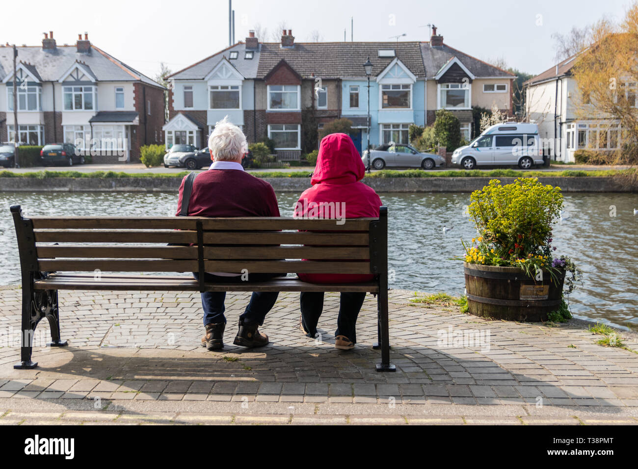 Couple de personnes âgées s'assit sur un banc en bois avec vue sur l'eau Banque D'Images