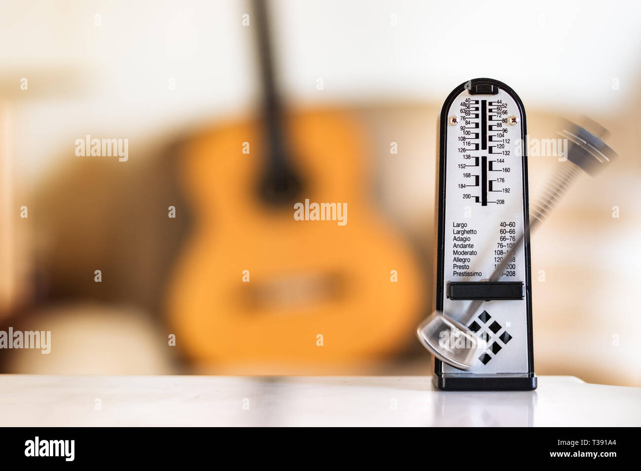Métronome mécanique en mouvement, sur une guitare acoustique classique en  arrière-plan Photo Stock - Alamy
