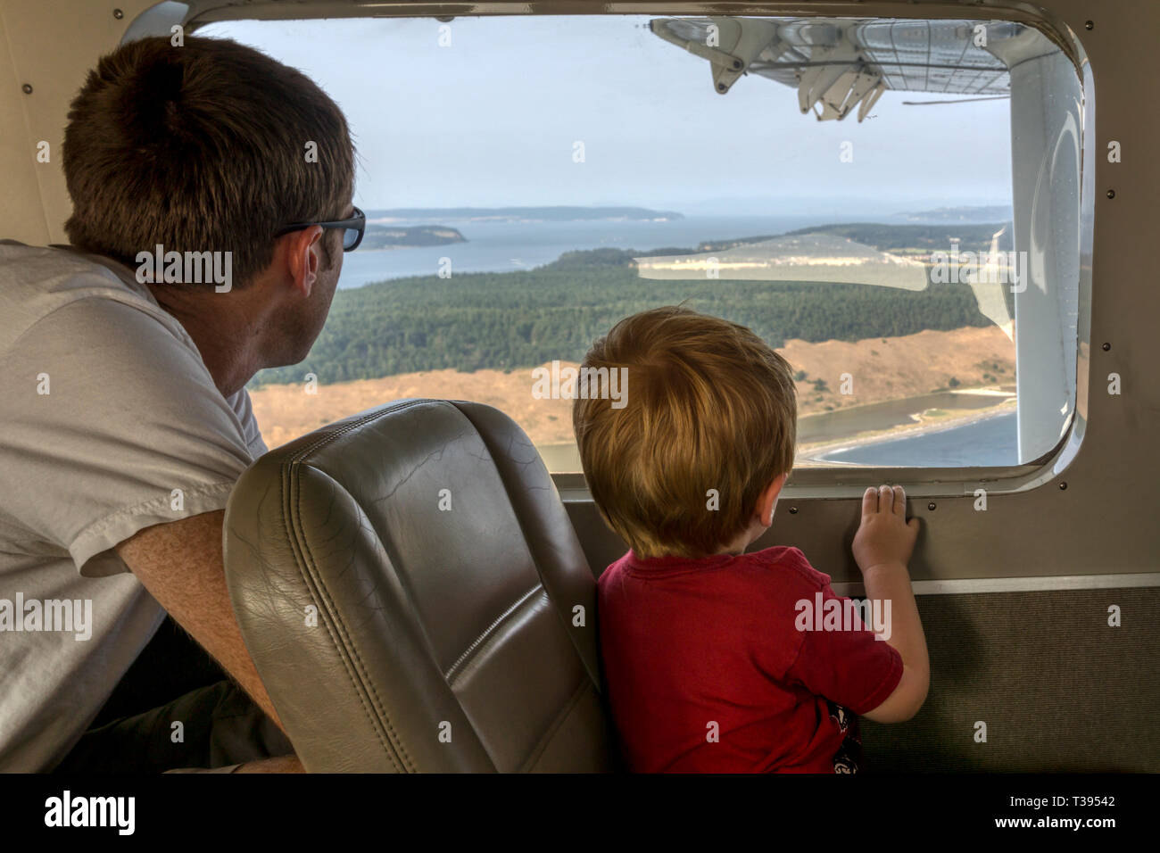 Un père & fils en regardant par la fenêtre d'un petit vol d'hydravion entre Seattle et les îles San Juan. Banque D'Images