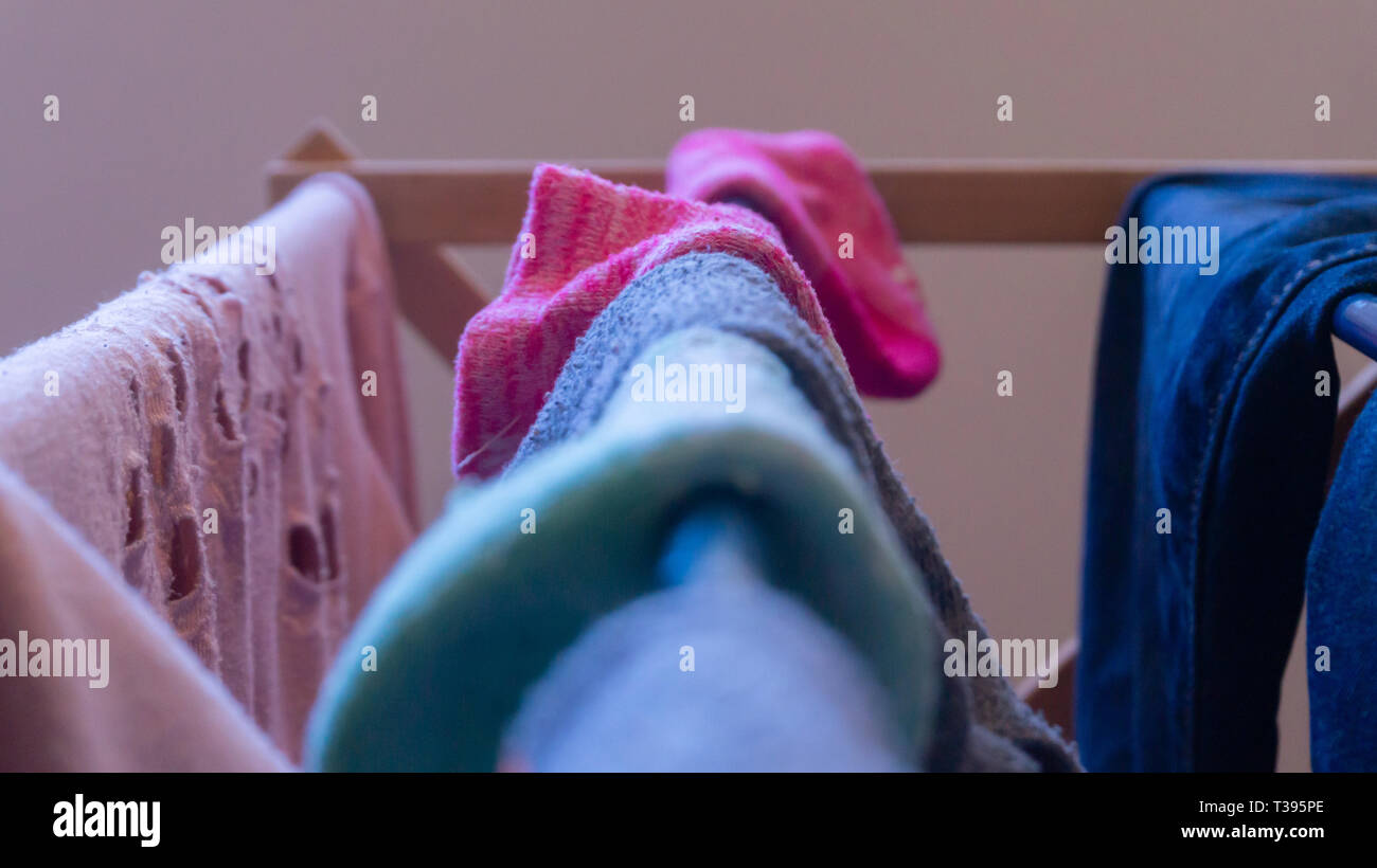 Se concentrer sur une chaussette rose le séchage sur un étendoir à linge avec d'autres vetements femme, chaussettes dépareillées et floues dans l'avant-plan. Dépeignant laundry day. Banque D'Images