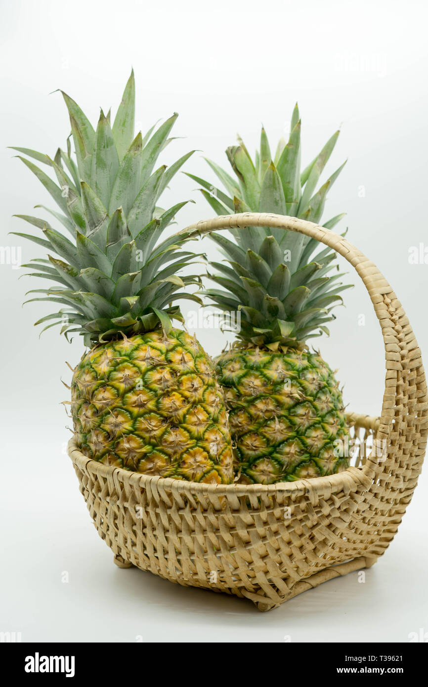 Photo de deux coudées d'ananas avec de grosses tiges dans un panier en osier  sur un cas isolé sur fond blanc Photo Stock - Alamy