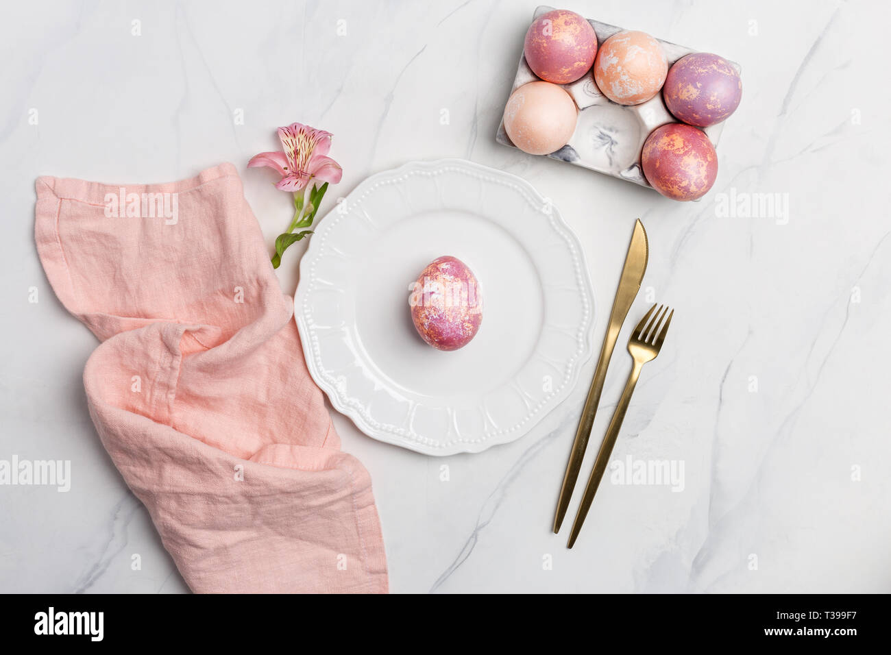 Table de Pâques, place. Œuf de Pâques, peint de couleur rose dans une assiette blanche, rose, serviette de table d'or avec fleur sur fond de marbre blanc, ve Banque D'Images Table de Pâques, place. Œuf de Pâques, peint de couleur rose dans une assiette blanche, rose, serviette de table d'or avec fleur sur fond de marbre blanc, ve Banque D'Images
