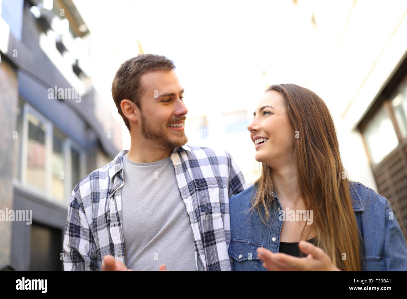 Vue frontale d'un heureux couple en train de marcher dans la rue à parler à l'autre Banque D'Images