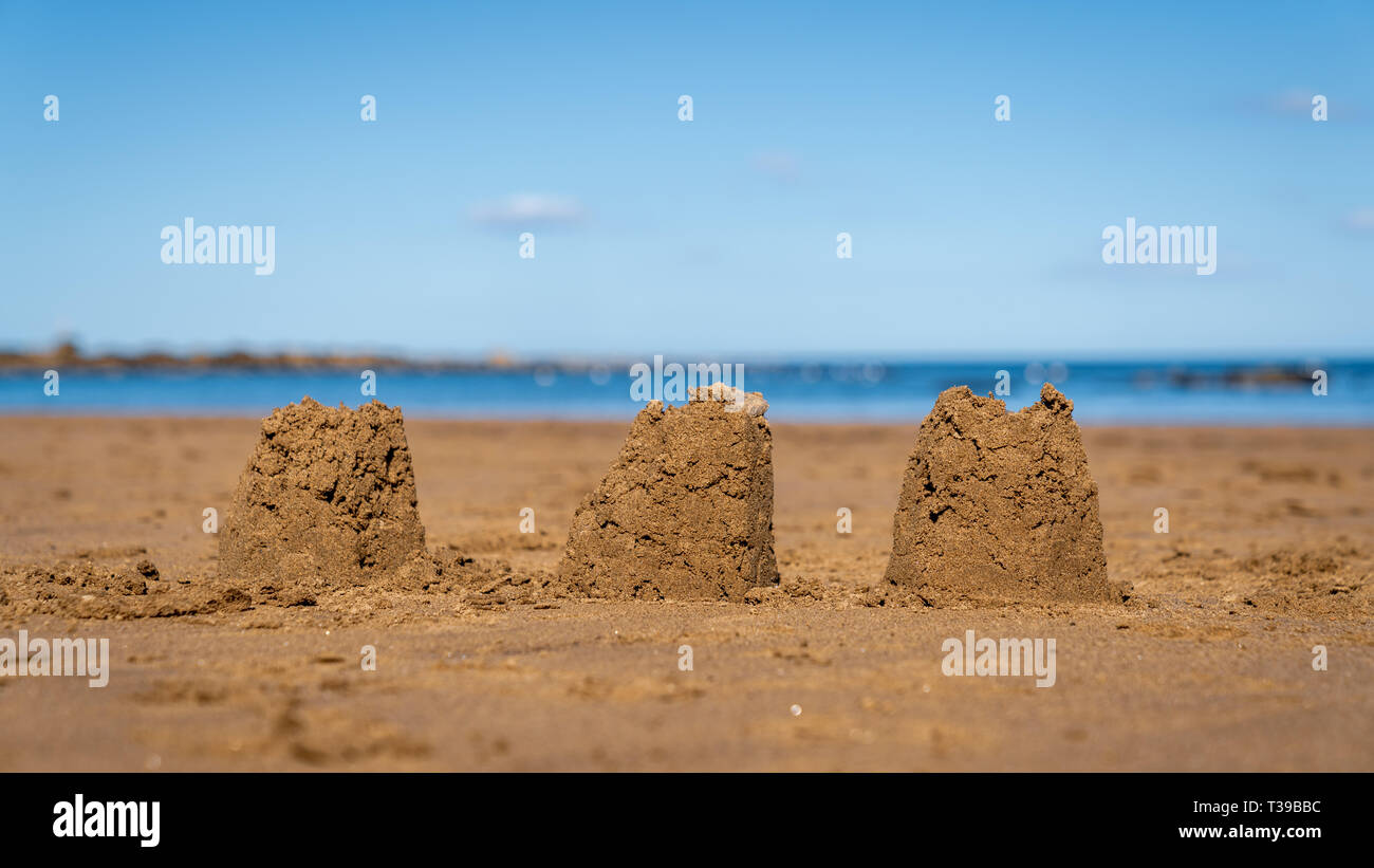 Châteaux de sable sur la plage de sables bitumineux, Runswick North Yorkshire, Angleterre Royaume-uni - avec la mer du Nord à l'arrière-plan Banque D'Images