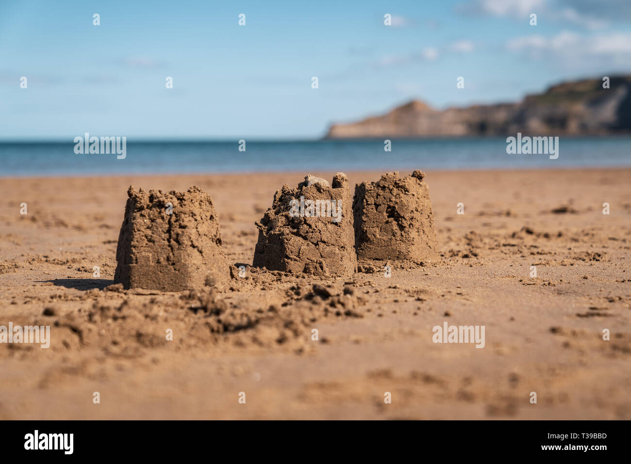 Châteaux de sable sur la plage de sables bitumineux, Runswick North Yorkshire, Angleterre Royaume-uni - Kettleness avec en arrière-plan Banque D'Images