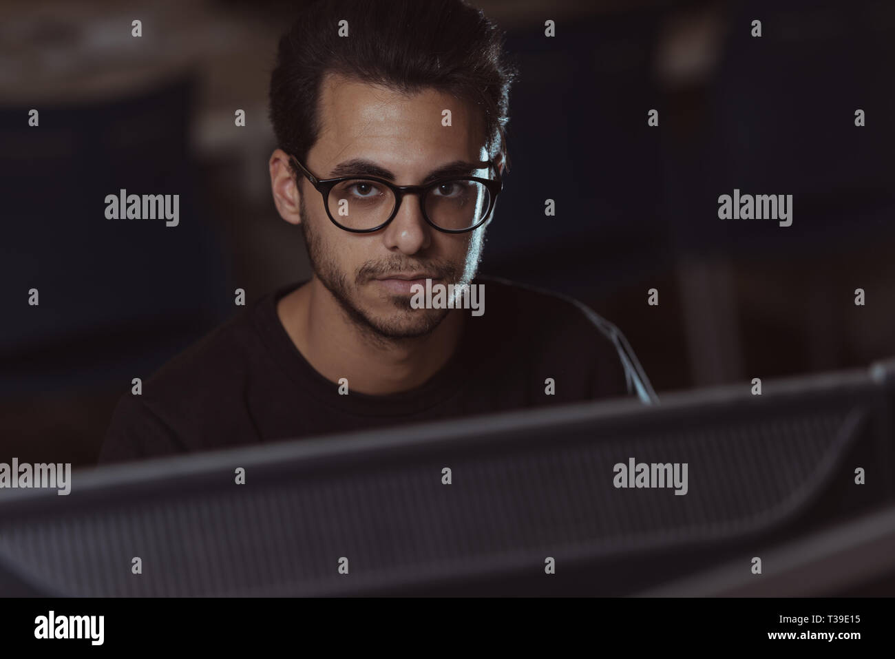 Vue sur un écran de la face d'un jeune étudiant en informatique travaillant avec l'ordinateur. Banque D'Images