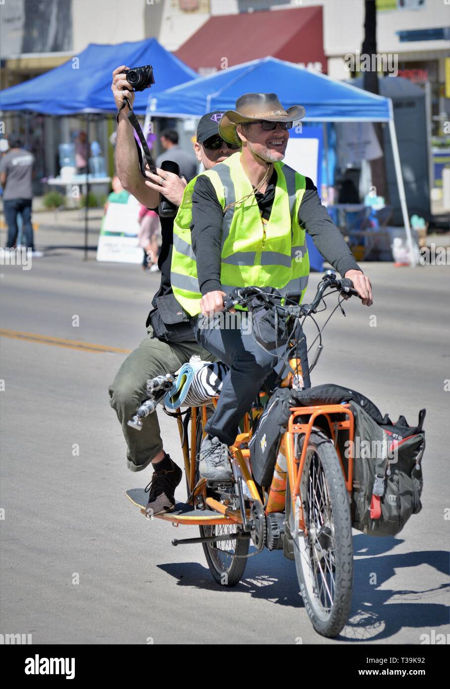 Homme pédalez à vélo pendant que son pilote fait un film de l'événement dans la rue publique avec un téléphone cellulaire appareil photo Banque D'Images
