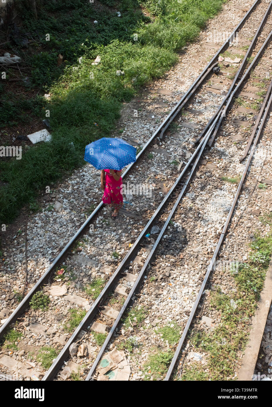 Femme avec parapluie à marcher le long de la voie de chemin de fer dans la région de Yangon, Myanmar (Birmanie) Banque D'Images