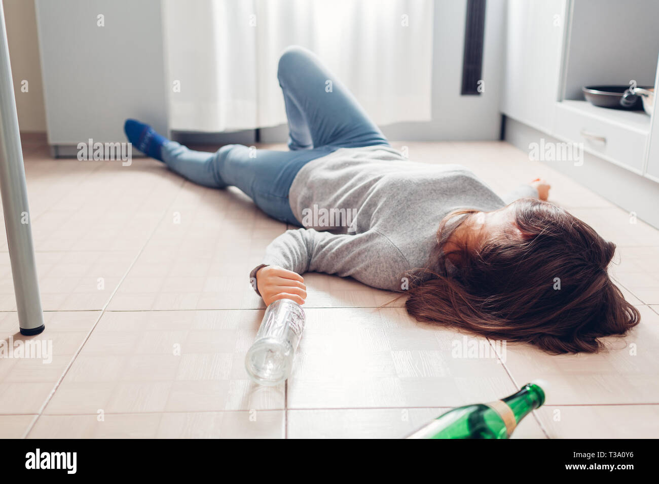 L'alcoolisme féminin. Jeune femme dormir sur plancher de la cuisine après  soirée entouré de bouteilles de vin. L'alcoolisme Photo Stock - Alamy