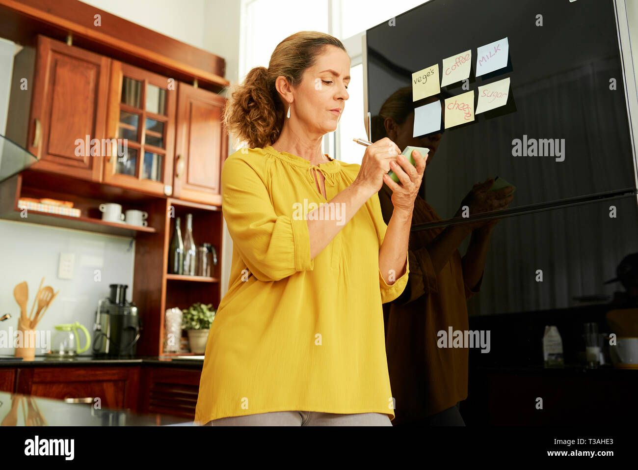 Femme au foyer s'en tenir des notes sur un réfrigérateur Banque D'Images