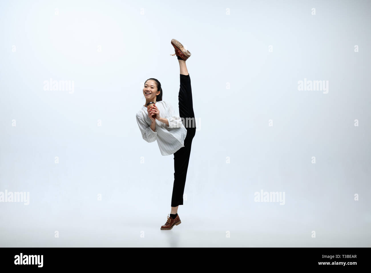 Commençons par l'arôme du café. Heureux femme travaillant à l'office, sauter et danser dans des vêtements décontractés ou costume isolated on white background studio. Entreprise, start-up, open-space de concept. Banque D'Images