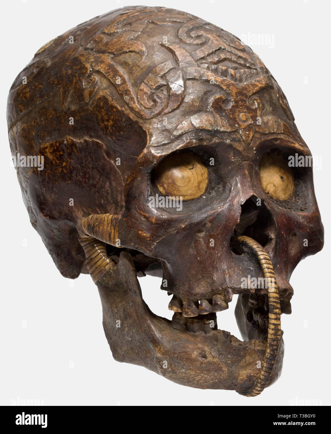 Un crâne trophée du Dayak, Borneo richement décorés du crâne, l'ensemble de la calotte entièrement sculptée d'ornements en relief, à l'os pariétal incrustations de coquillage à droite et à gauche. Les orbites fermées avec des coquillages. Le pot inférieur à l'aide d'un filet en rotin. L'ensemble crâne patiné fortement, quelques dents en moins, quelques parties avec de petites fissures. Hauteur 21 cm. Les Dayak sont la population indigène de l'île de Bornéo et comprennent plusieurs centaines de petits groupes ethniques, dont certains se différencier considérablement, Additional-Rights Clearance-Info-REG-Not-Available Banque D'Images