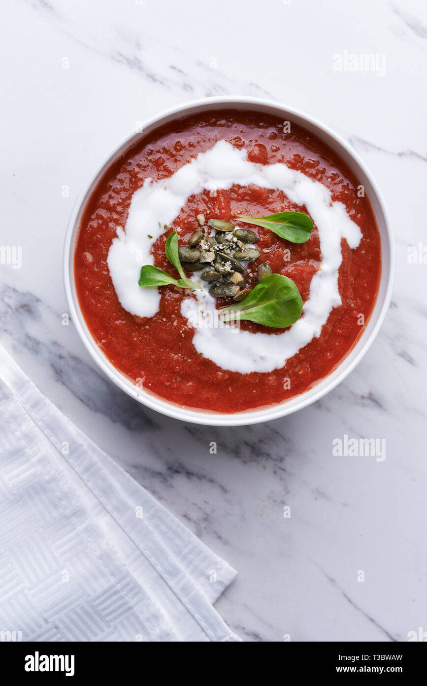 Soupe crème de tomates avec les graines de citrouille dans un bol blanc Banque D'Images