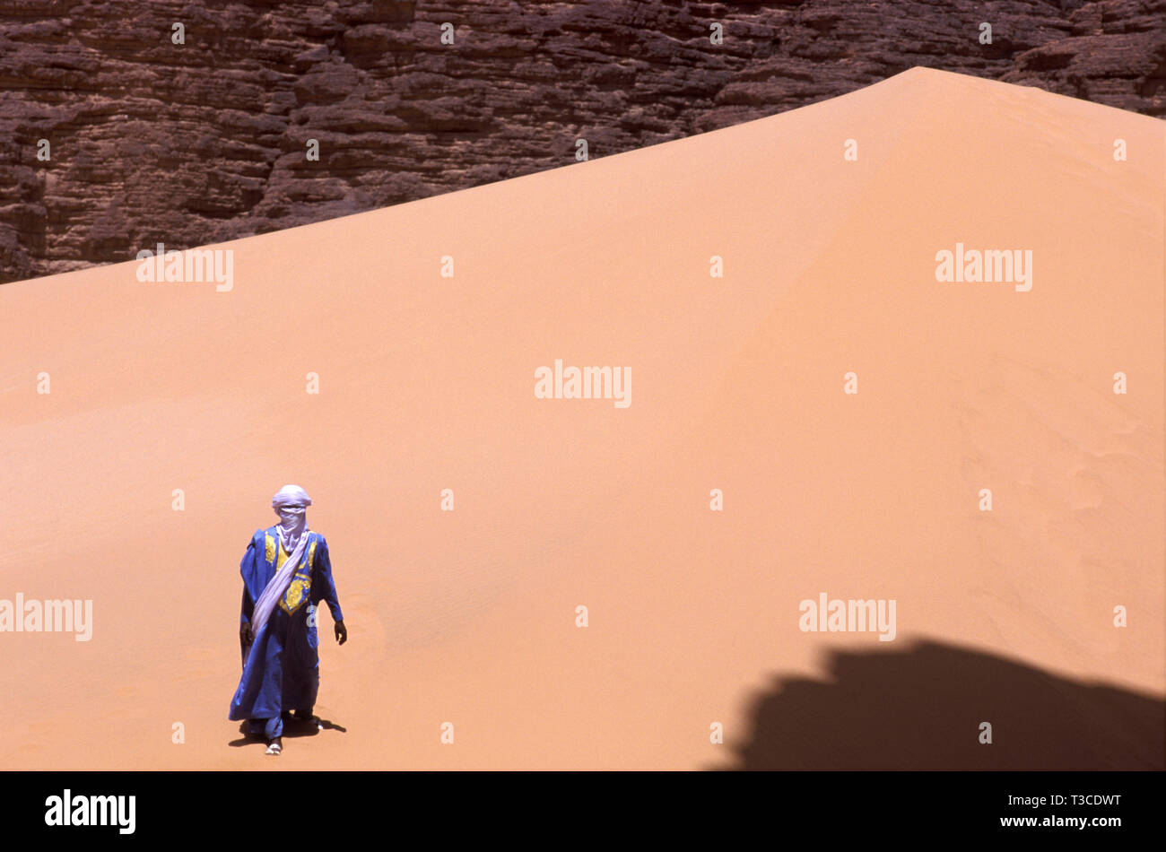 Homme touareg dans un costume traditionnel, marcher sur une dune, l'Algérie Banque D'Images