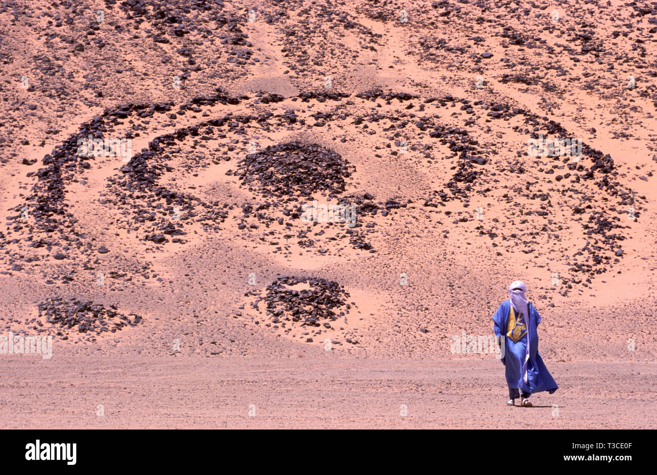 Homme touareg dans un costume traditionnel, avec une année 5000 vieille tombe en arrière-plan dans le Sahara en Algérie Banque D'Images Homme touareg dans un costume traditionnel, avec une année 5000 vieille tombe en arrière-plan dans le Sahara en Algérie Banque D'Images