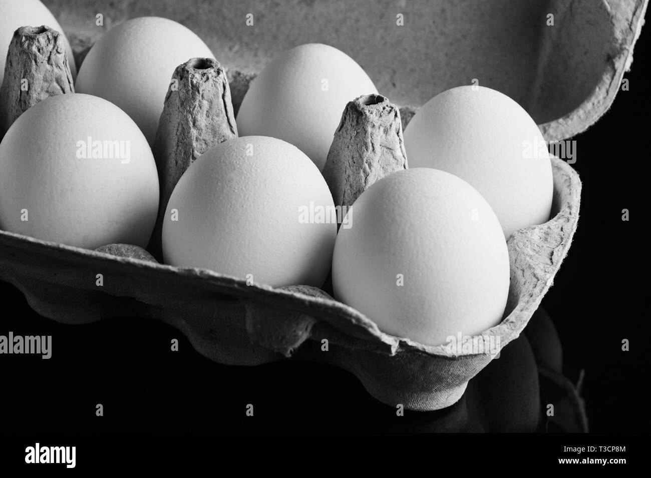 Des œufs frais dans l'emballage ouvert sur fond noir Banque D'Images