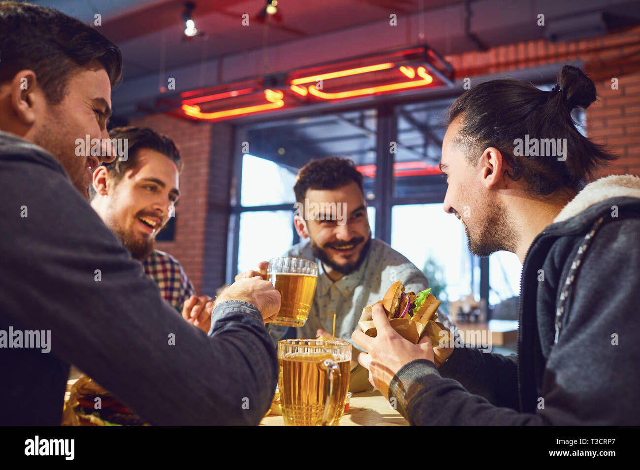 Heureux les amis manger des hamburgers, boire de la bière dans un bar. Banque D'Images