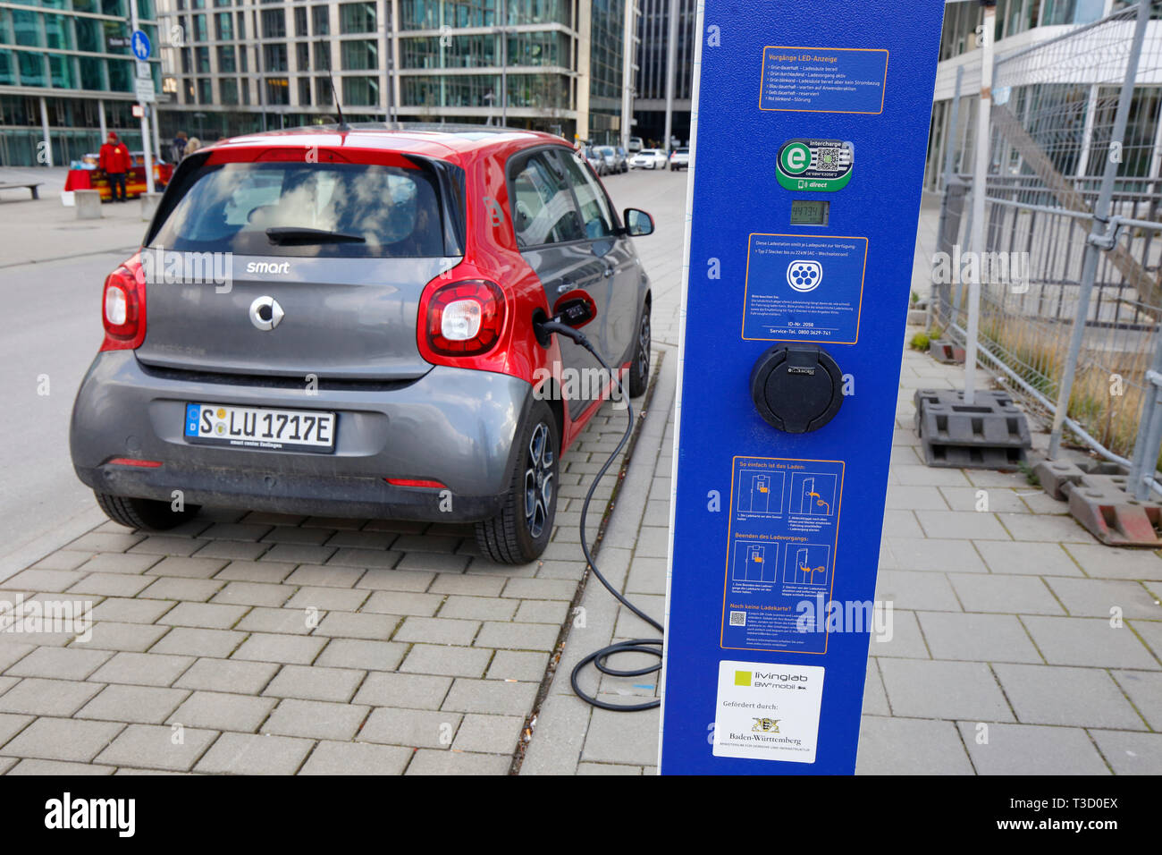 Une voiture Smart se recharge à une station de charge de voiture électrique en bordure de rue à Stuttgart, Allemagne Banque D'Images
