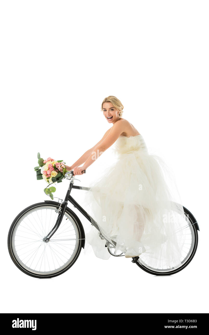 Belle groom riding bicycle in robe de mariage tout en maintenant mariage bouquet isolated on white Banque D'Images