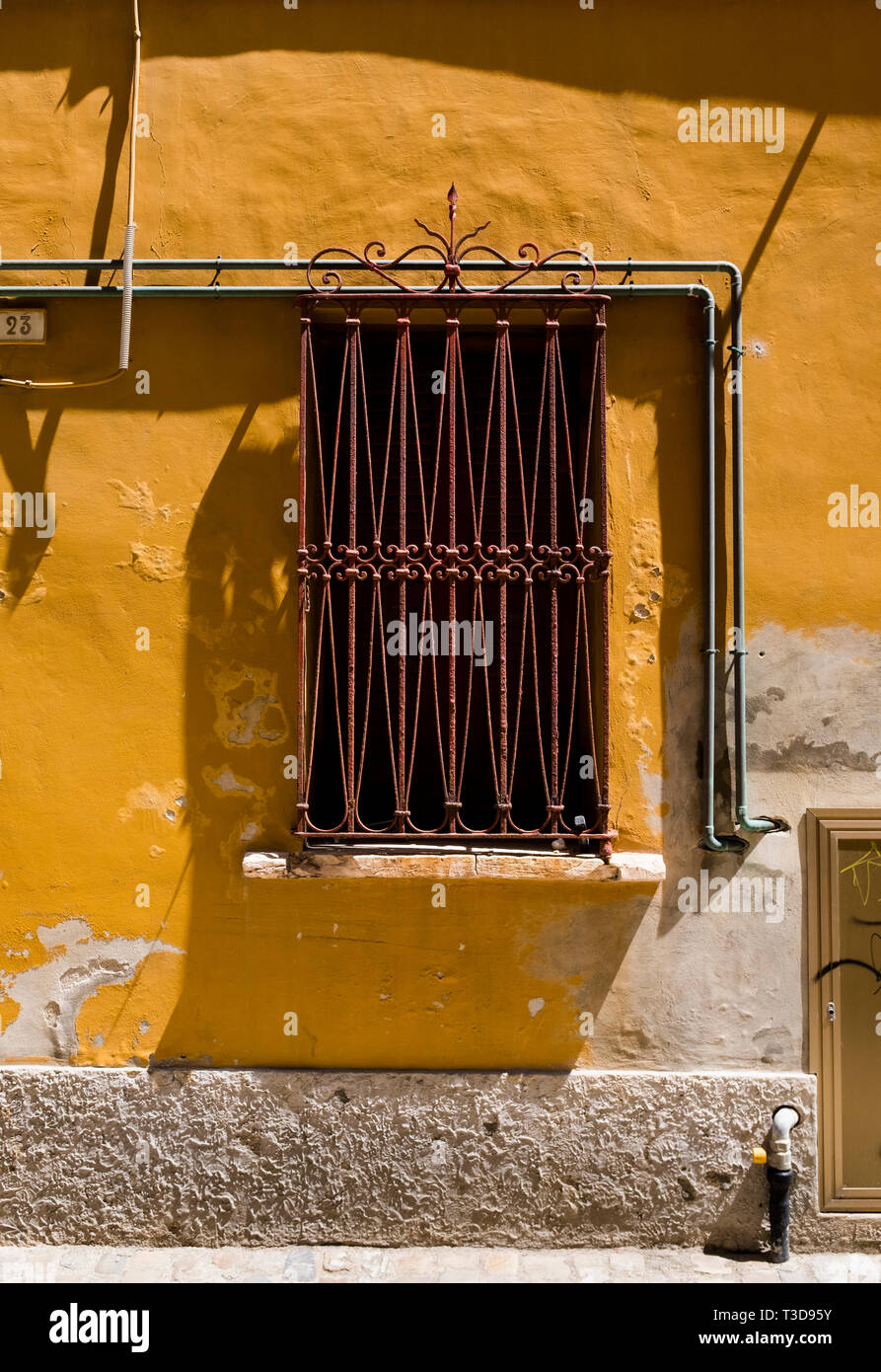 Détail d'une grille rouillée, fenêtre ouvragée et mur de plâtre jaune dans les rues de Fano, Italie Banque D'Images