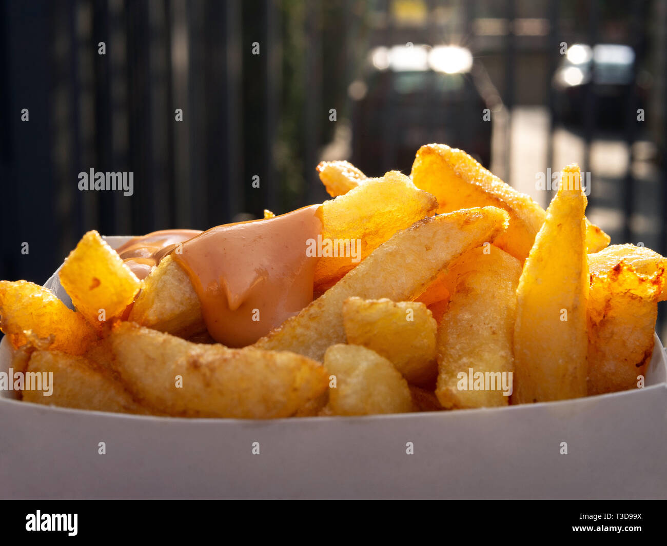 Fort de frites avec sauce. Gros plan sur une boîte de frites avec sauce. La lumière du jour, l'arrière-plan flou derrière. Concept de restauration rapide et les aliments malsains. Banque D'Images