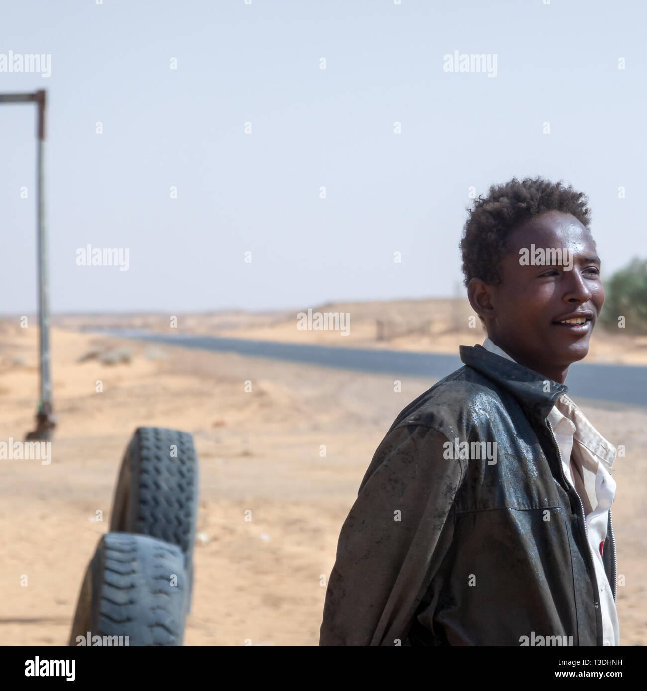 Kerma, au Soudan, le 8 février, 2019. : Jeune homme souriant soudanais en portrait sur la route à travers le désert dans le nord du Soudan avec de vieux cuir usé jmd Banque D'Images