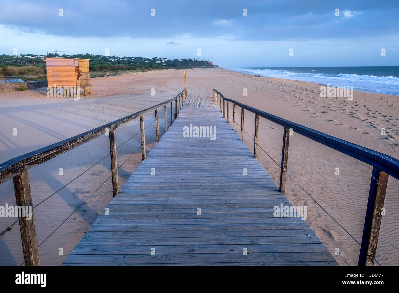 En regardant un decking en bois avec garde-corps en bois de chaque côté, la trajectoire est sur une grande plage de sable de balayage et mène à san pur Banque D'Images