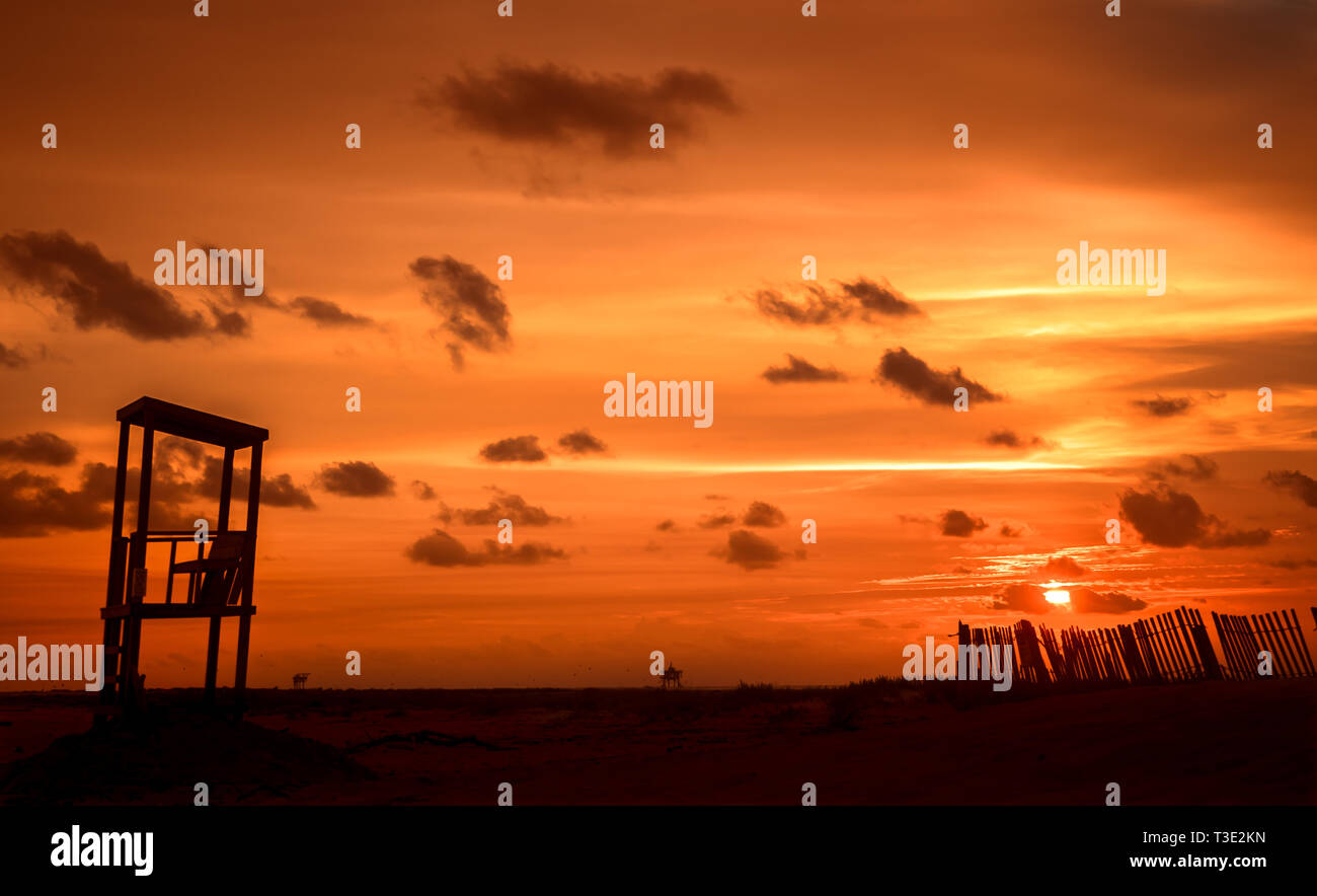 Le soleil se couche derrière une barrière de sable et de secours sur l'extrémité ouest de Dauphin Island, Alabama. Banque D'Images