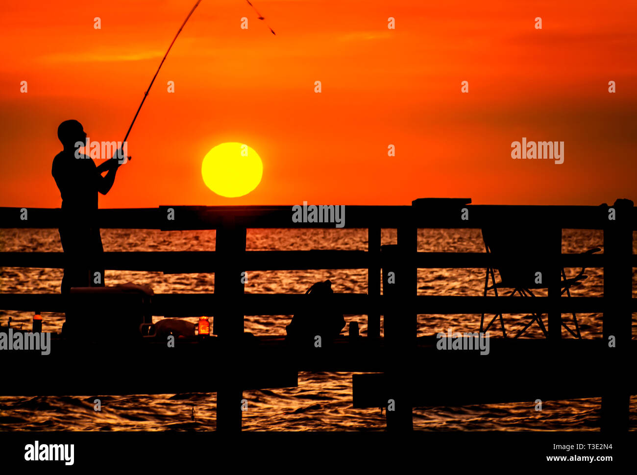 Un homme se profile par le coucher de soleil qu'il pêche, 1 juillet 2013, au quai de pêche de Cedar Point sur la côte du golfe de l'Alabama. Banque D'Images