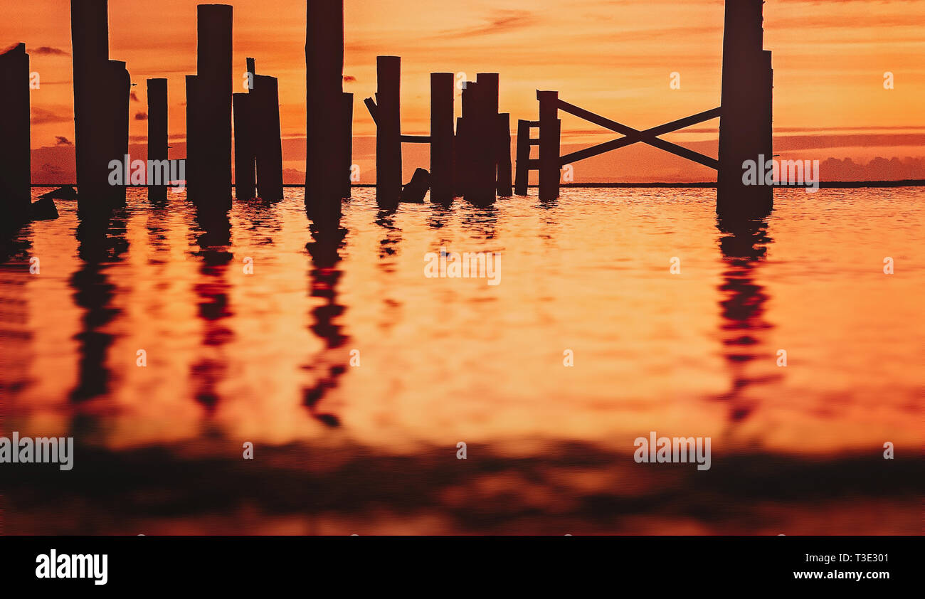 Le soleil se couche sur l'eau, silhouetting un quai, à la coupe dans Coden, Alabama. Banque D'Images