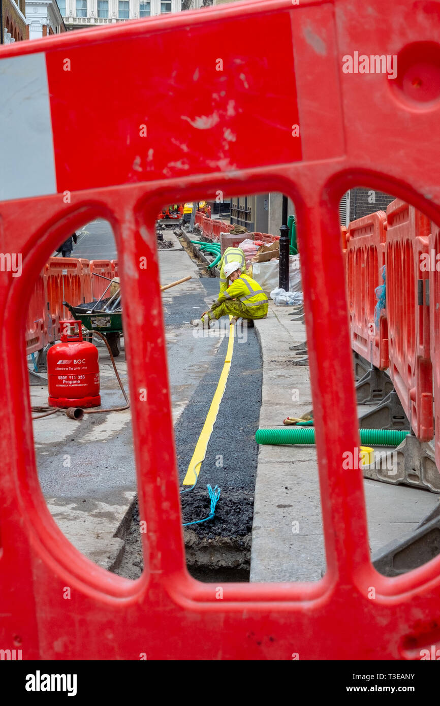 Les travailleurs de la construction du délire à John Adam street dans le West End de Londres pour poser des câbles de télécommunications à large bande de fibre. Banque D'Images