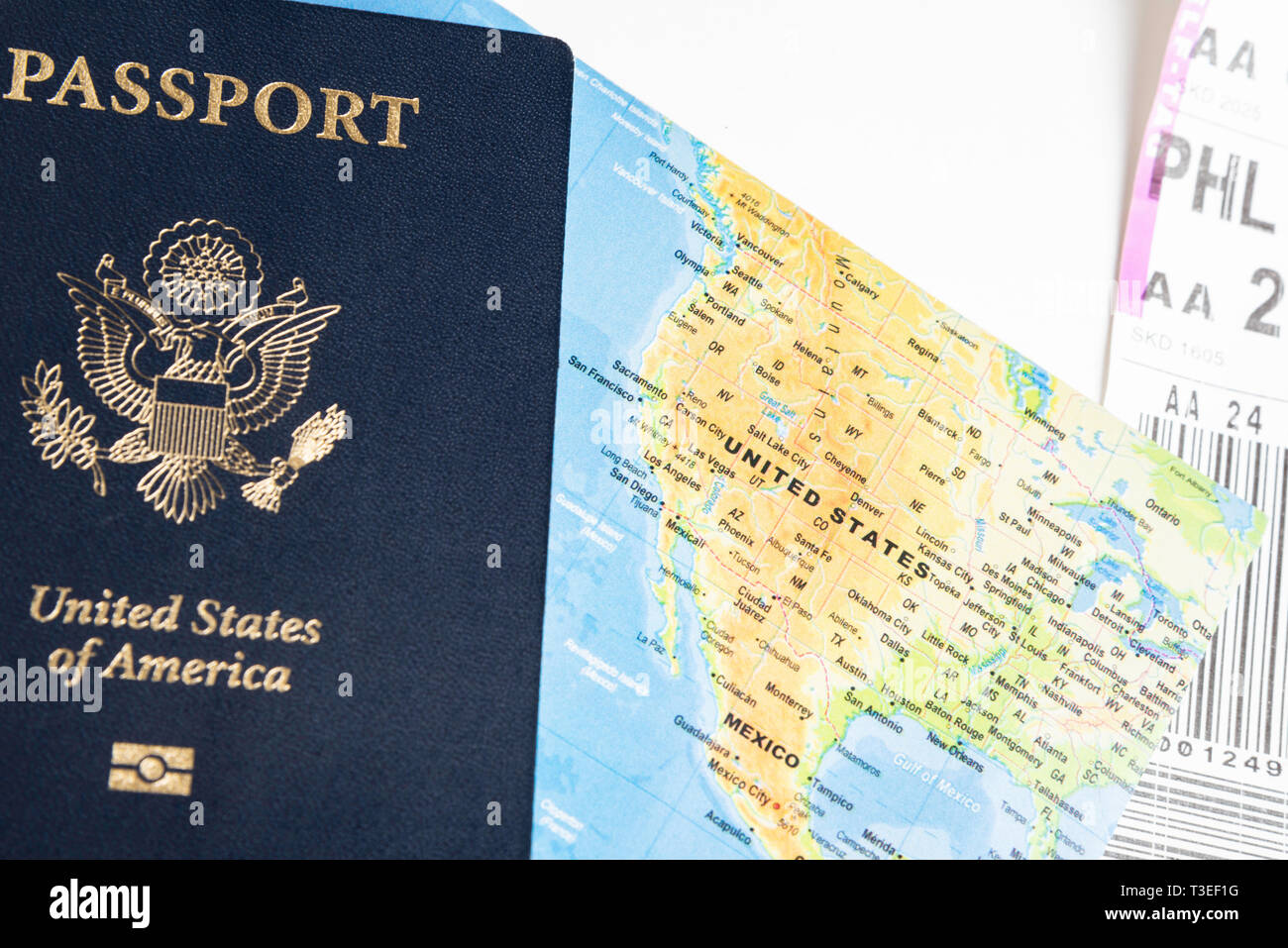 L'emblématique avec couverture bleu foncé avec de l'or du cachet du passeport américain avec des portions de carte pliée et porte-étiquette astucieusement situé sur fond blanc. Banque D'Images