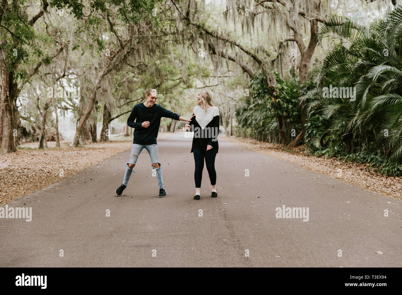 Cute Young Happy couple aimant marcher dans une ancienne route abandonnée avec les arbres surplombant Mossy Oak Banque D'Images