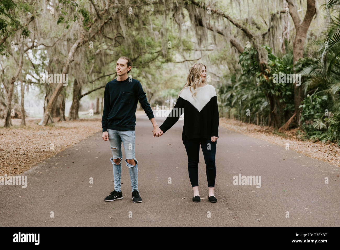 Cute Young Happy couple aimant marcher dans une ancienne route abandonnée avec les arbres surplombant Mossy Oak Banque D'Images