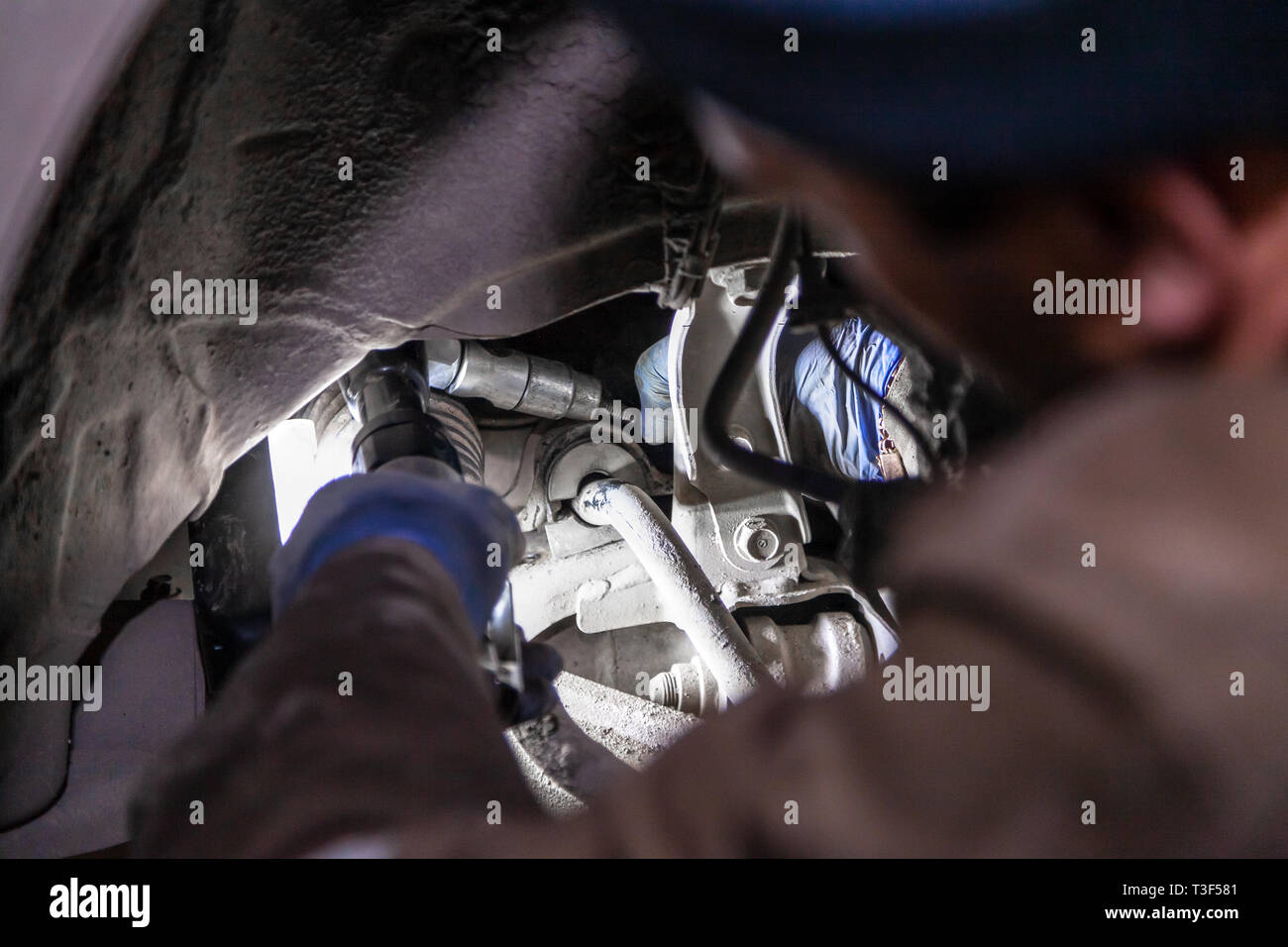 Close up Professional mécanicien de voiture rend les réparations au châssis d'une voiture pris en charge en service de réparation automobile. Changements dans les manchons Autoworker garage Banque D'Images