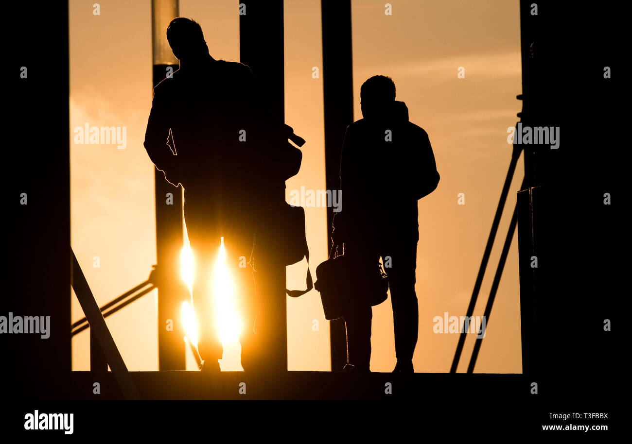 Hanovre, Allemagne. 09 avr, 2019. Deux hommes à pied porte-documents à lever du soleil sur un pont à l'Expo Plaza. Credit : Julian Stratenschulte/dpa/Alamy Live News Banque D'Images