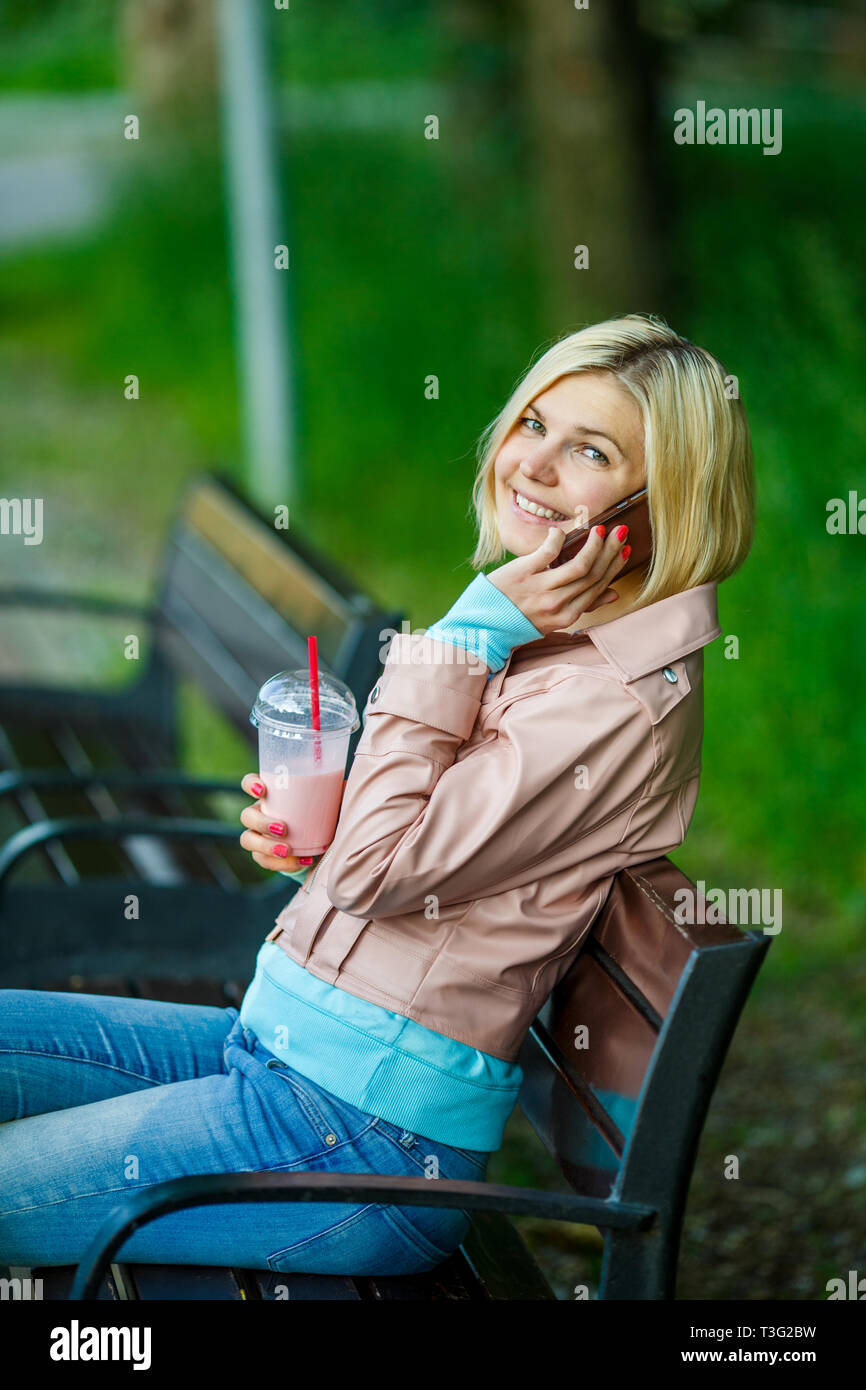 Femme avec milkshake et téléphone Banque D'Images