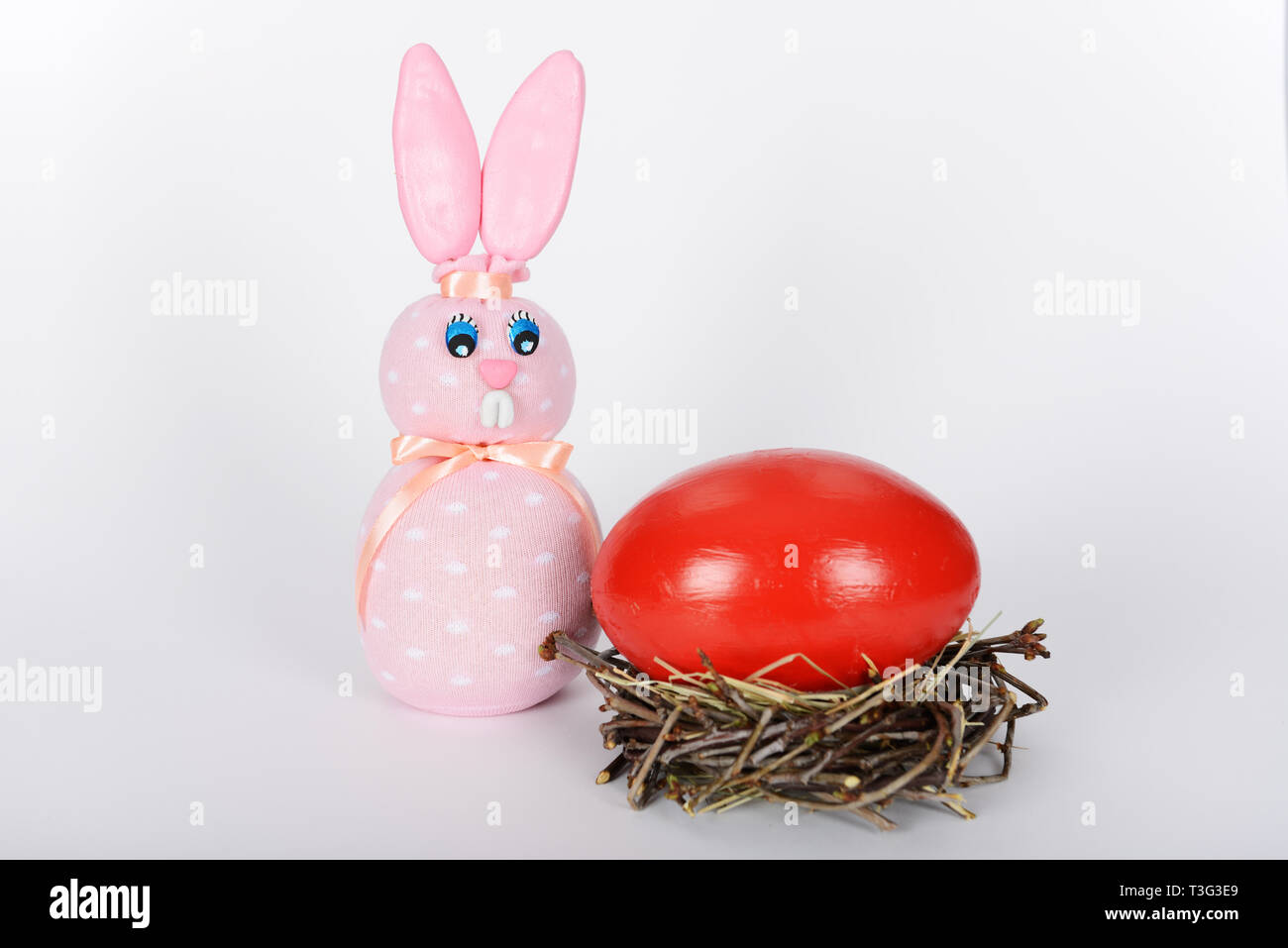 Le fait-main rose lapin de Pâques et le nid avec big red painted easter egg d'autruche Banque D'Images